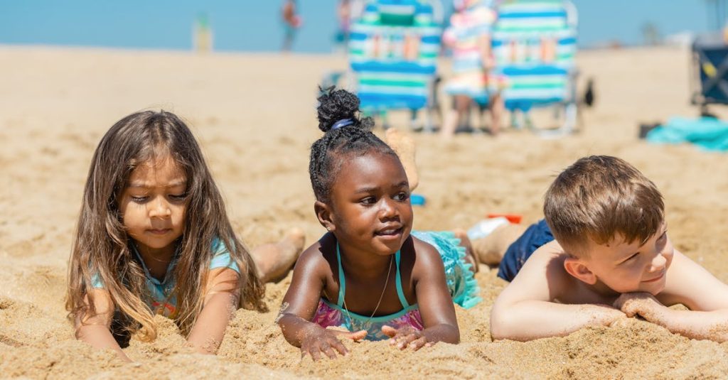 Three children enjoying a sunny day at the beach, playing in the sand.