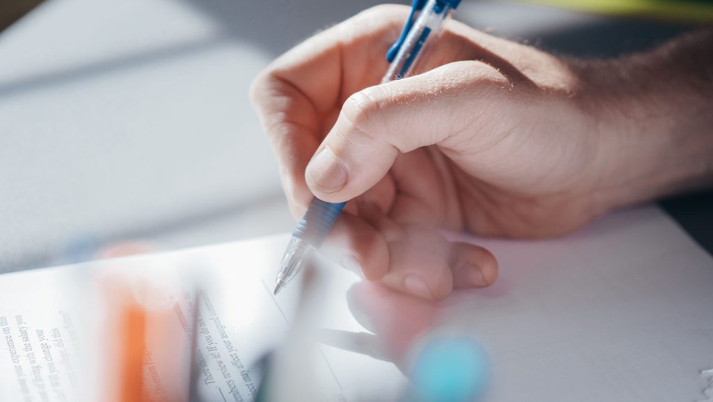 Focused shot of a hand writing with a pen, highlighting concentration and creativity.
